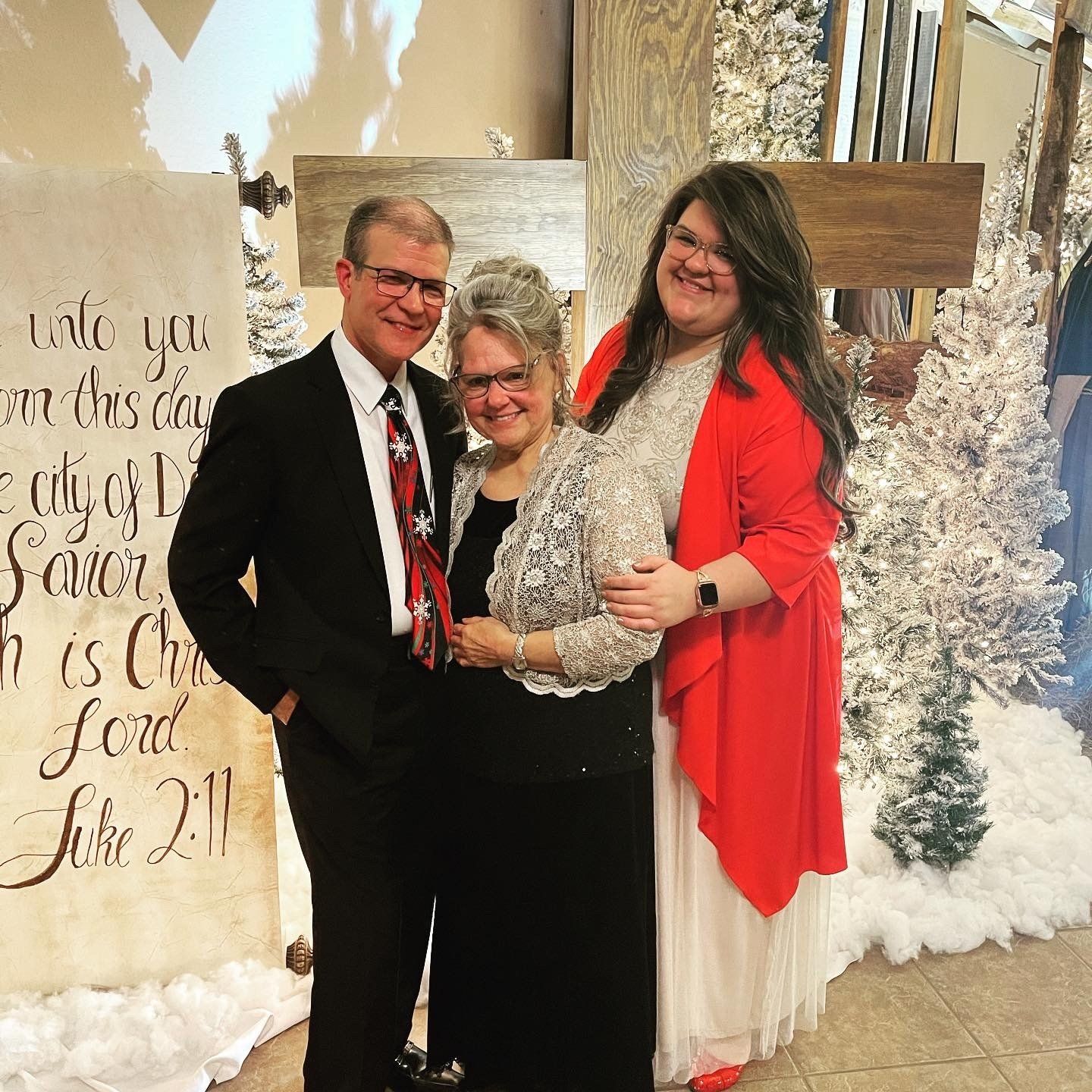A man and two women standing in front of a sign that says luke 2:11