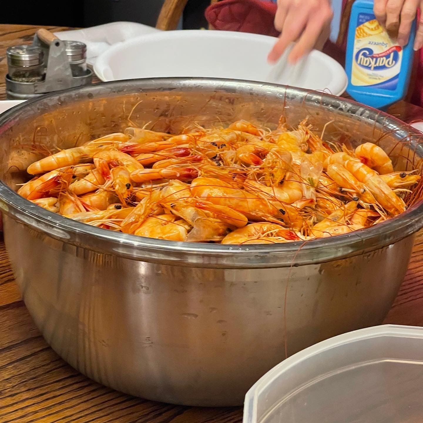 A bowl of shrimp sits on a table next to a bottle of aquafina