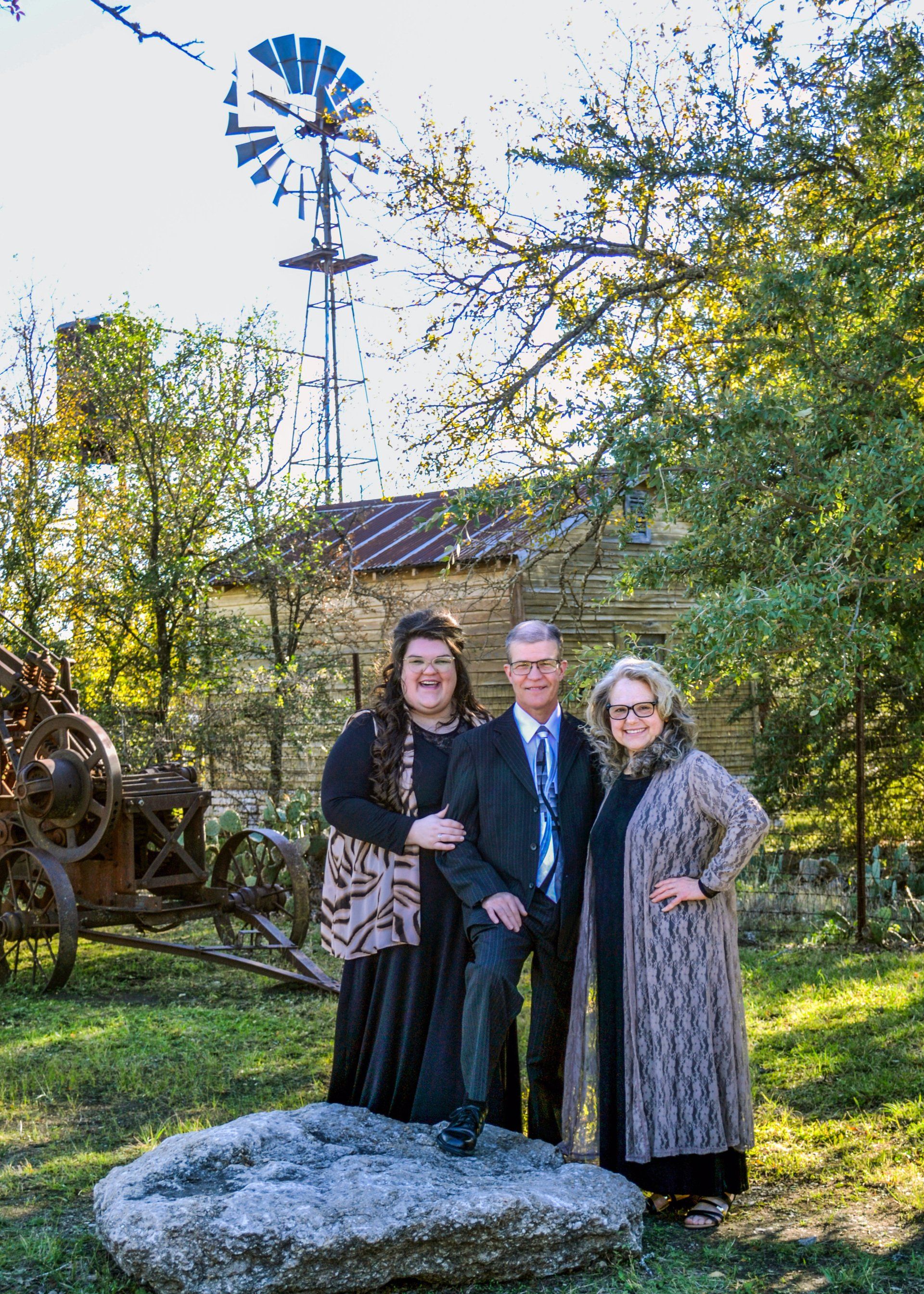 A group of people standing next to each other in front of a windmill.