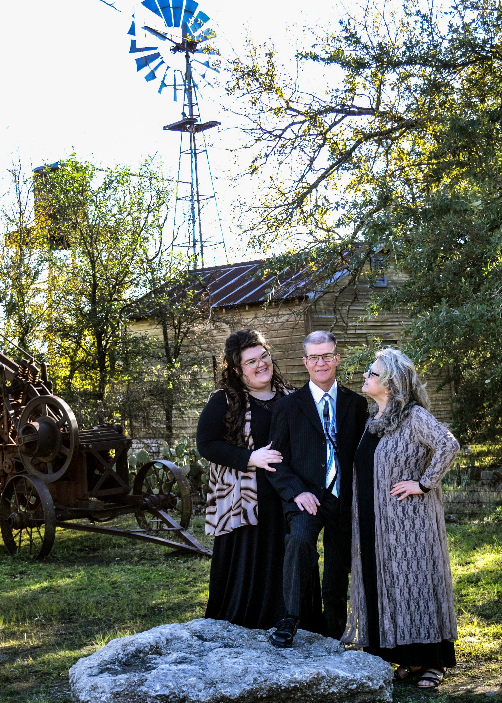 A man and two women are posing for a picture in front of a windmill.