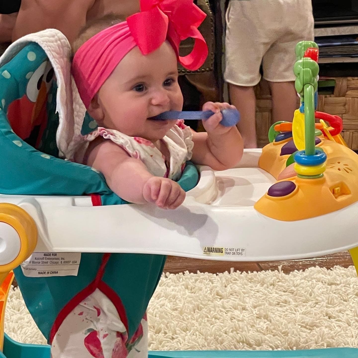A baby wearing a pink headband is sitting in a high chair