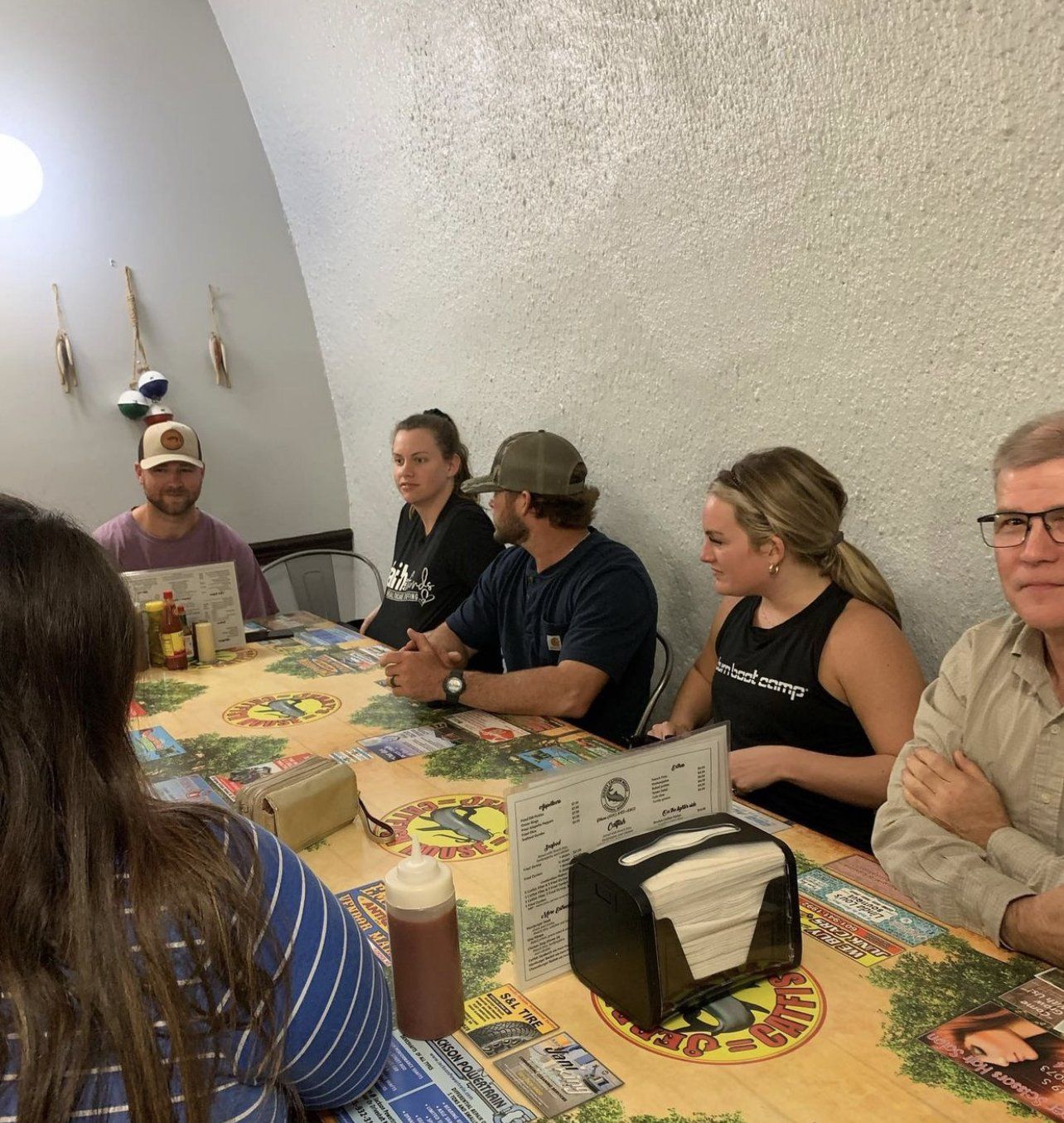 A group of people are sitting around a table with a napkin holder on it