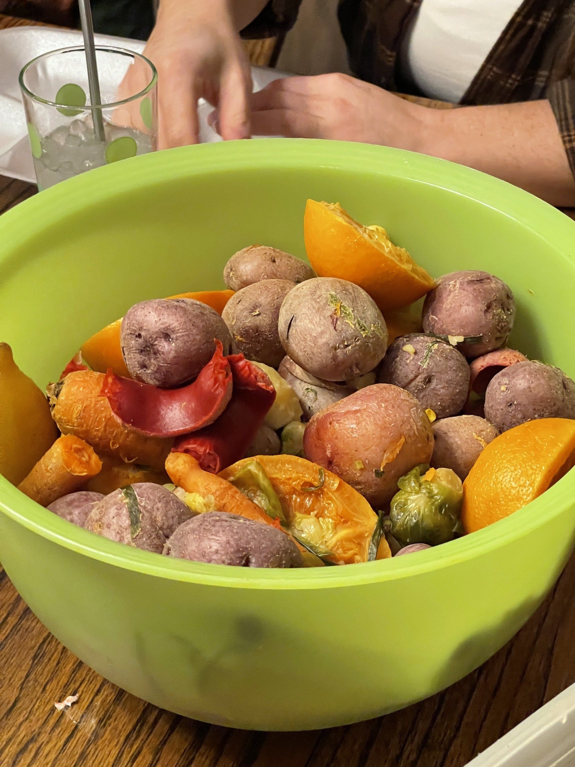 A green bowl filled with potatoes and oranges