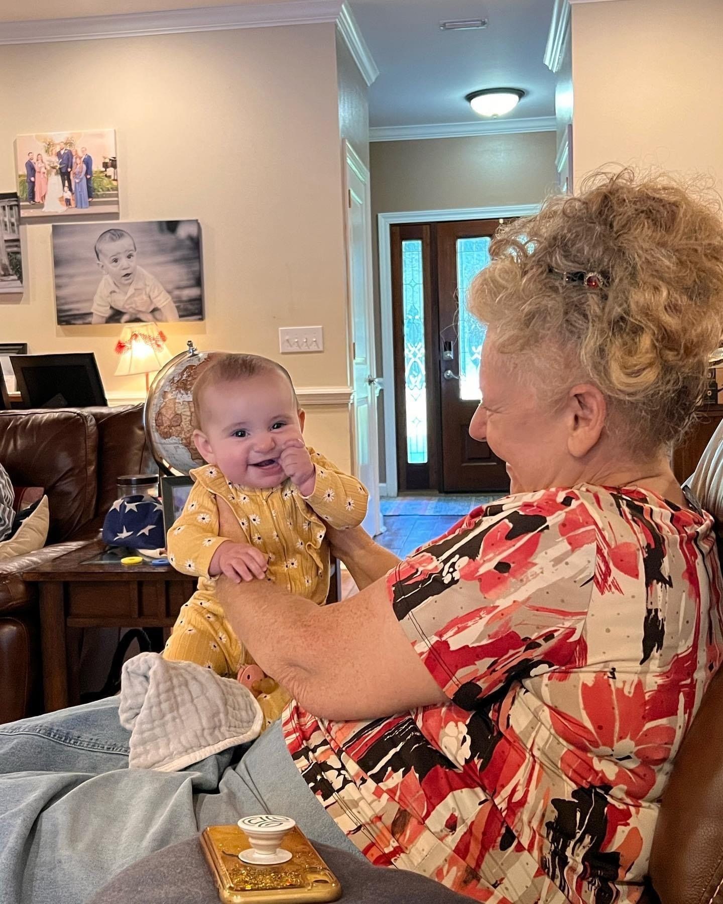 A woman is holding a baby in her lap in a living room.