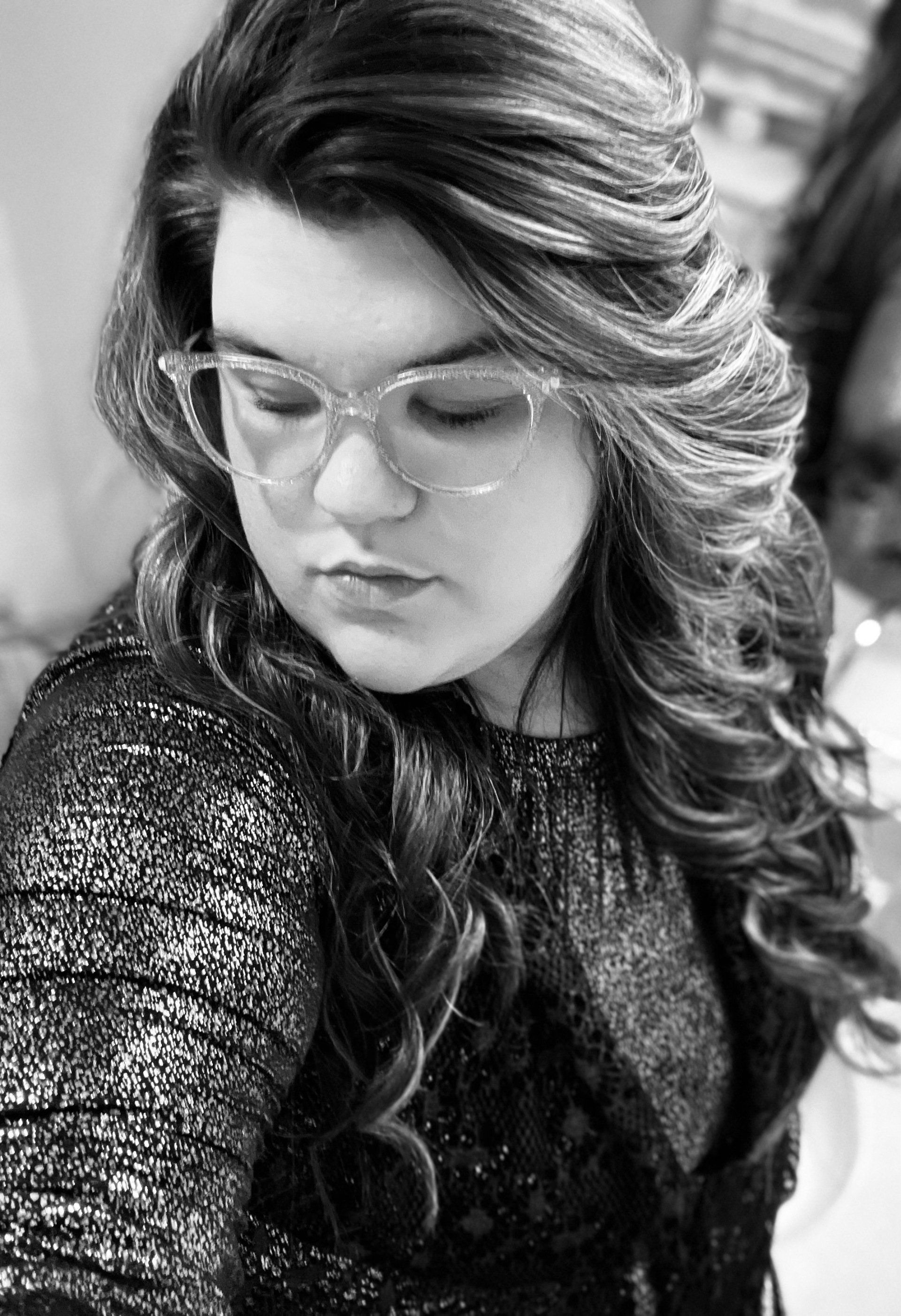 A black and white photo of a woman wearing glasses and a sweater.