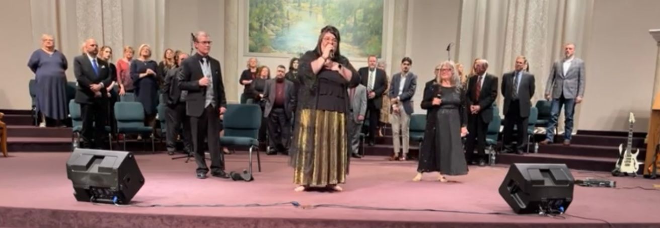 Trio singing in front of a large choir