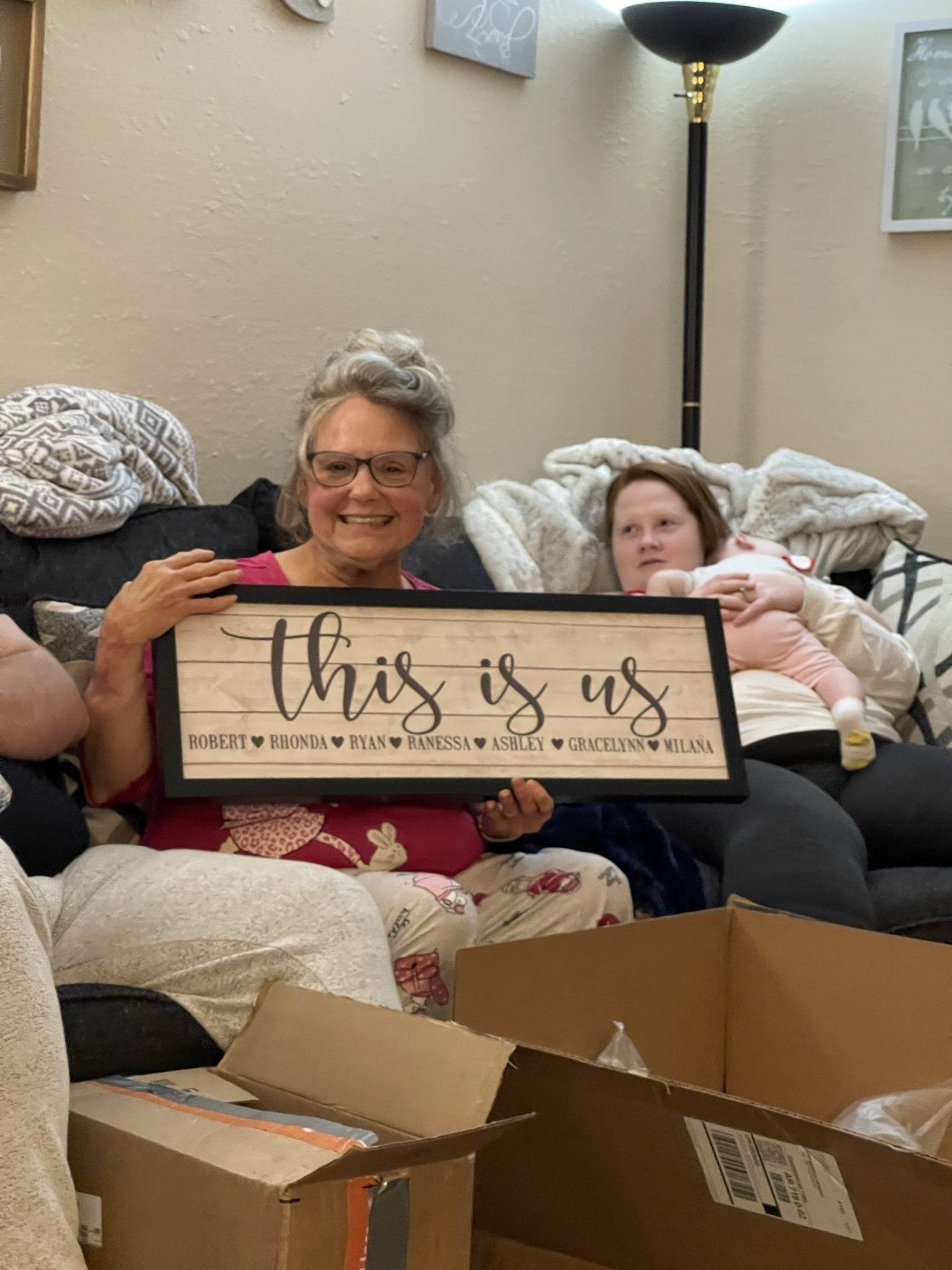 A woman is holding a sign that says `` this is us '' while sitting on a couch.