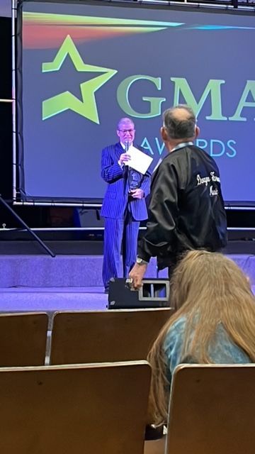 A man in a suit stands in front of a gma logo