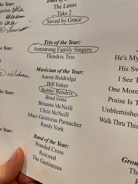 A person is holding a piece of paper that says trio of the year
