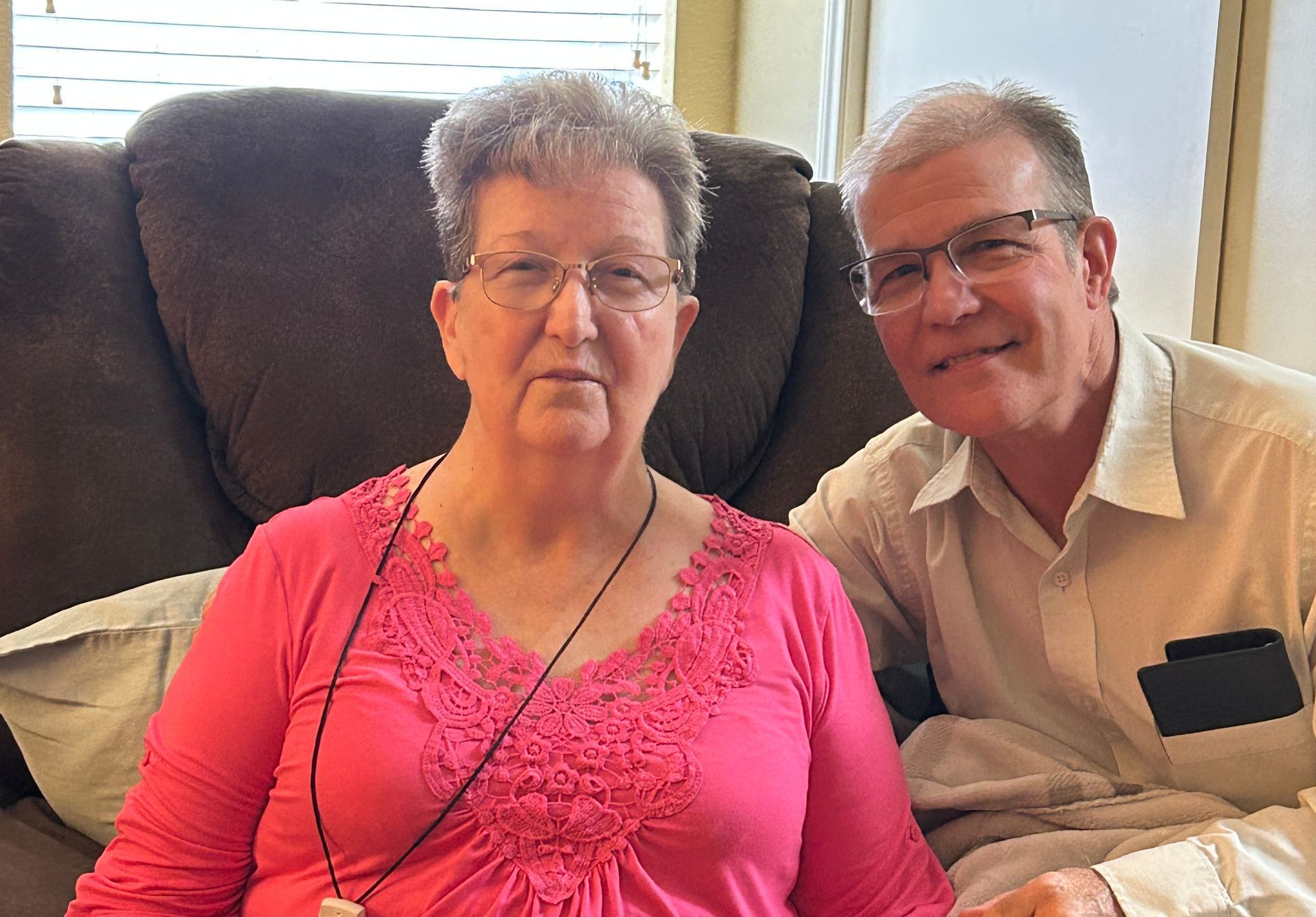 lady sitting smiling. man with arm around her smiling