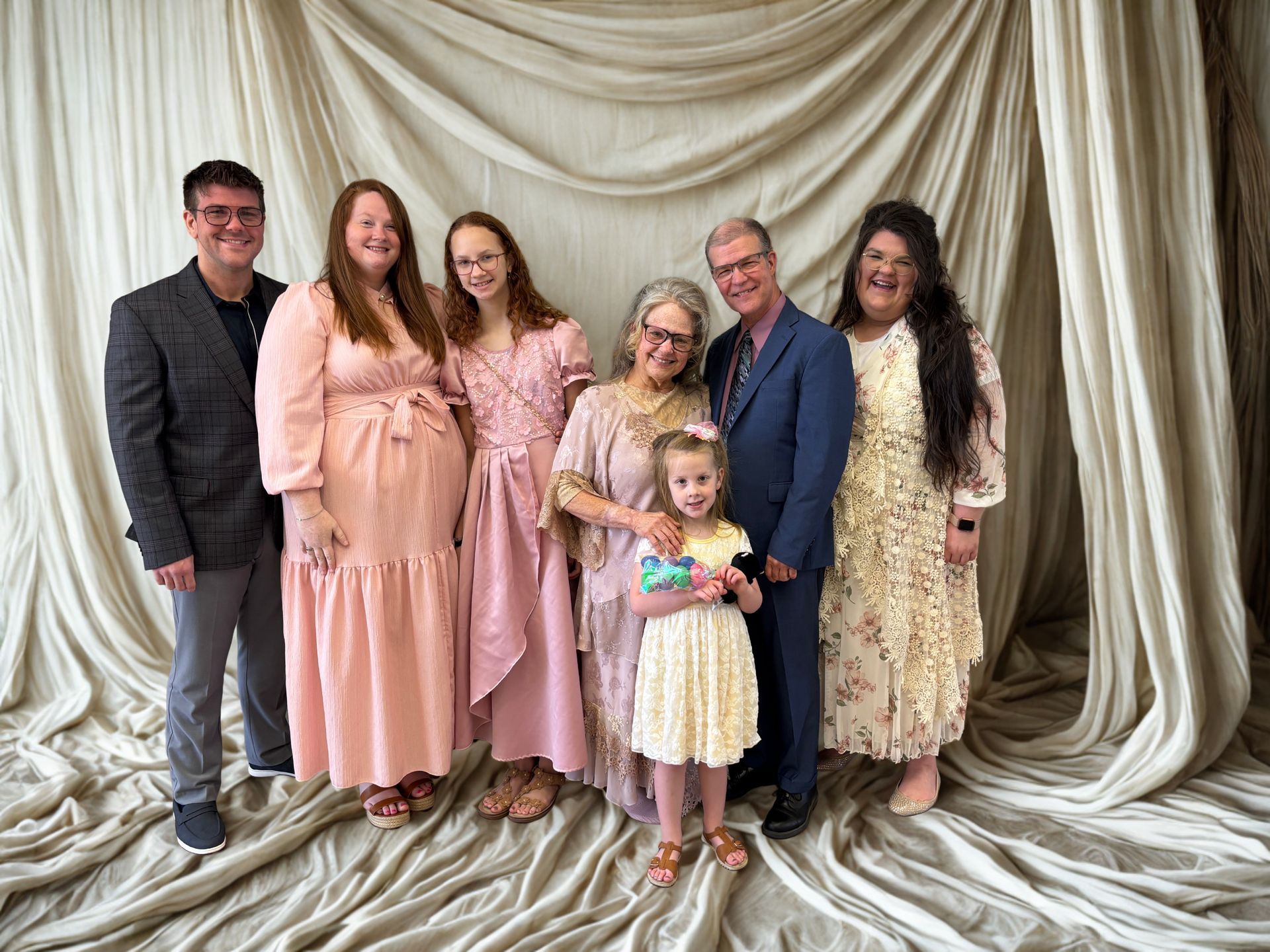 family of 7 standing in front of curtains posing