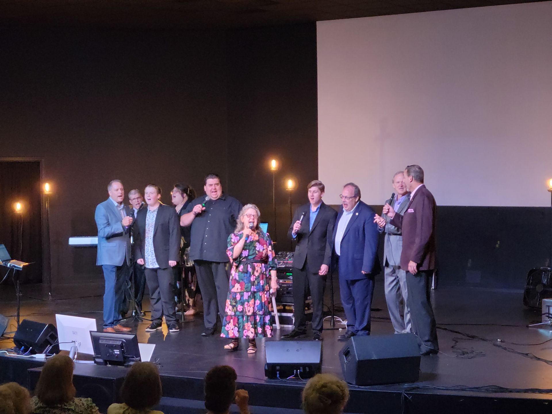A group of people are standing on a stage in front of a microphone.