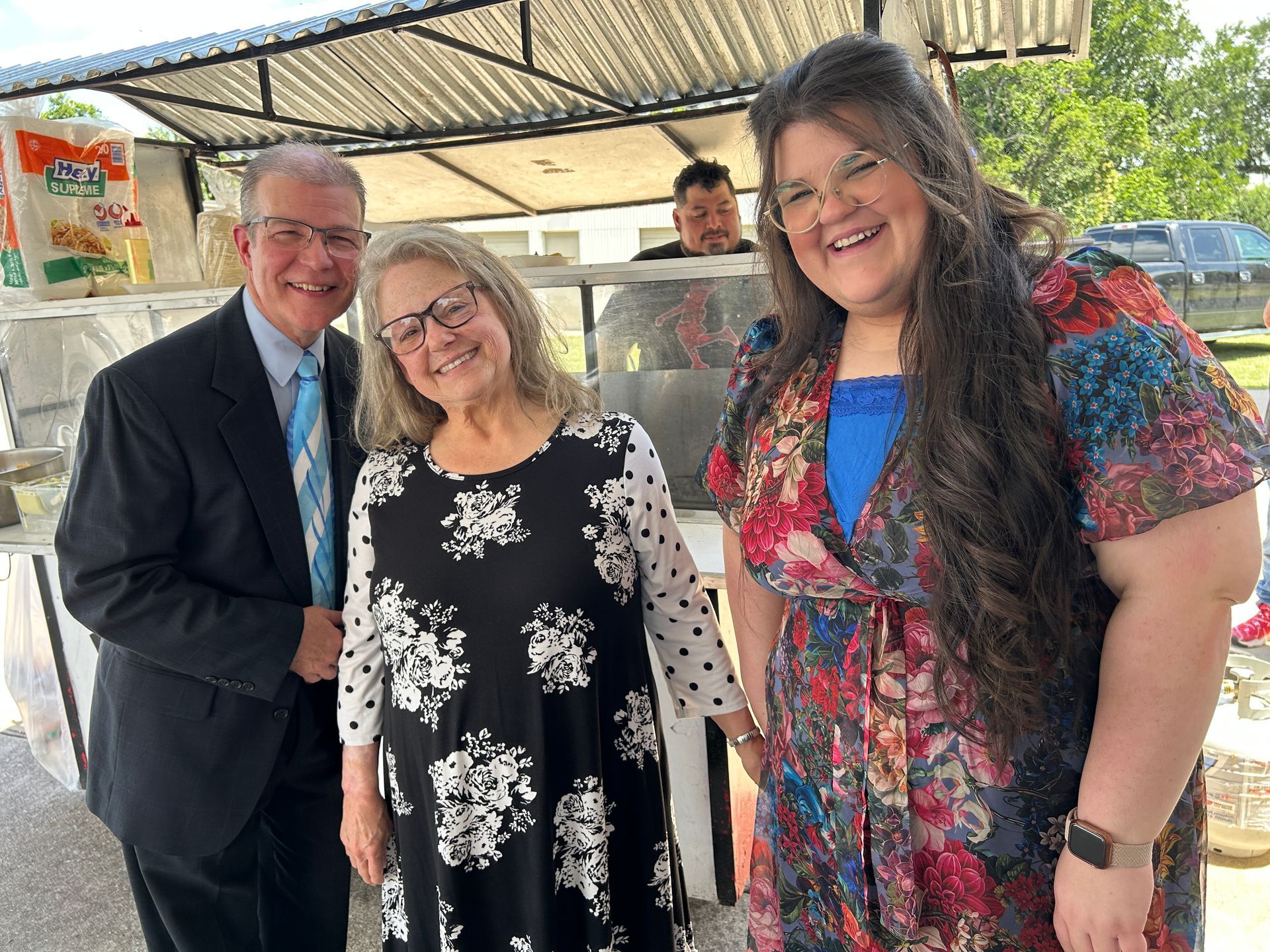 three people standing in front of a taco truck