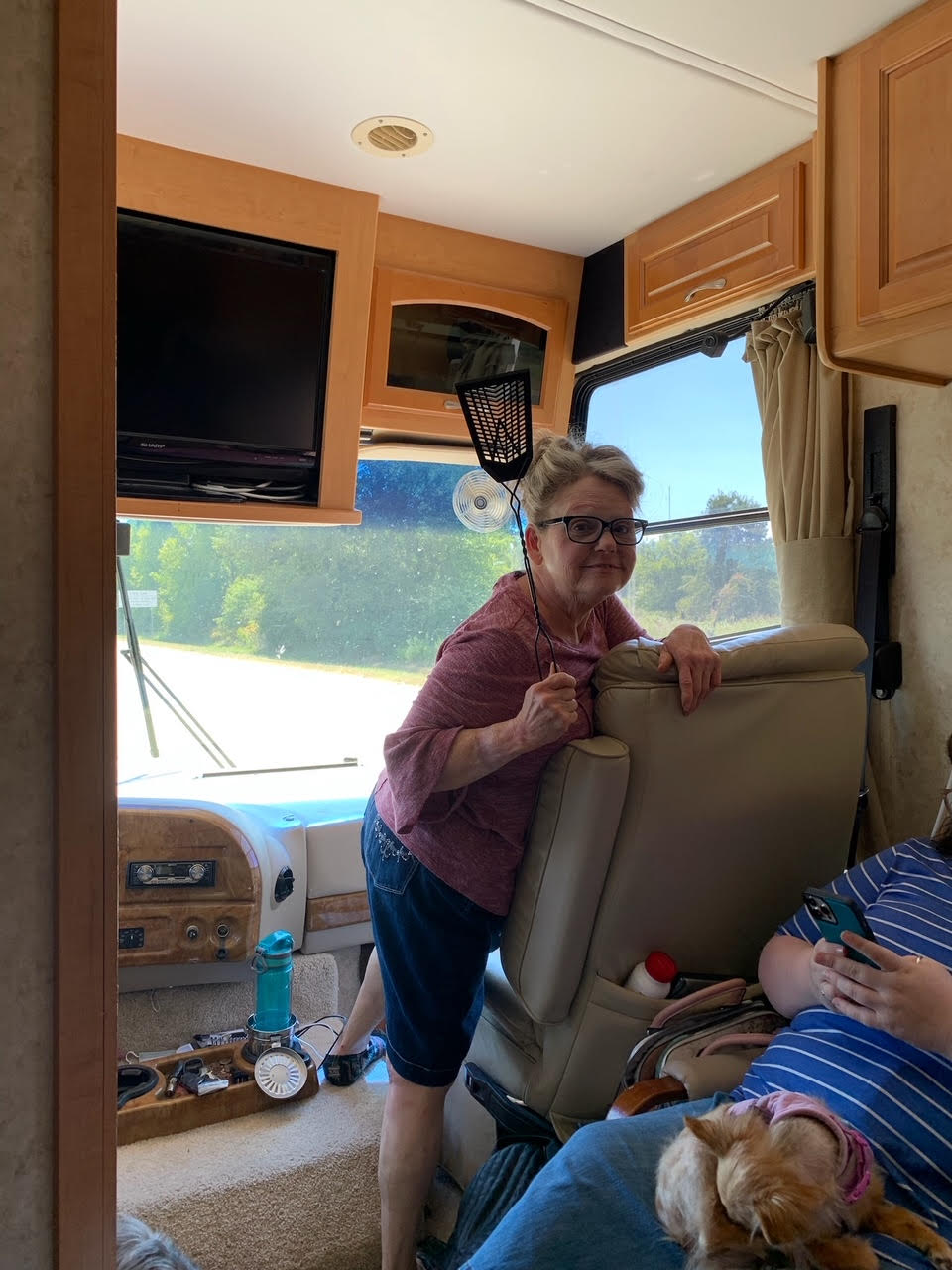 A woman is standing next to a man sitting in a chair in a rv.