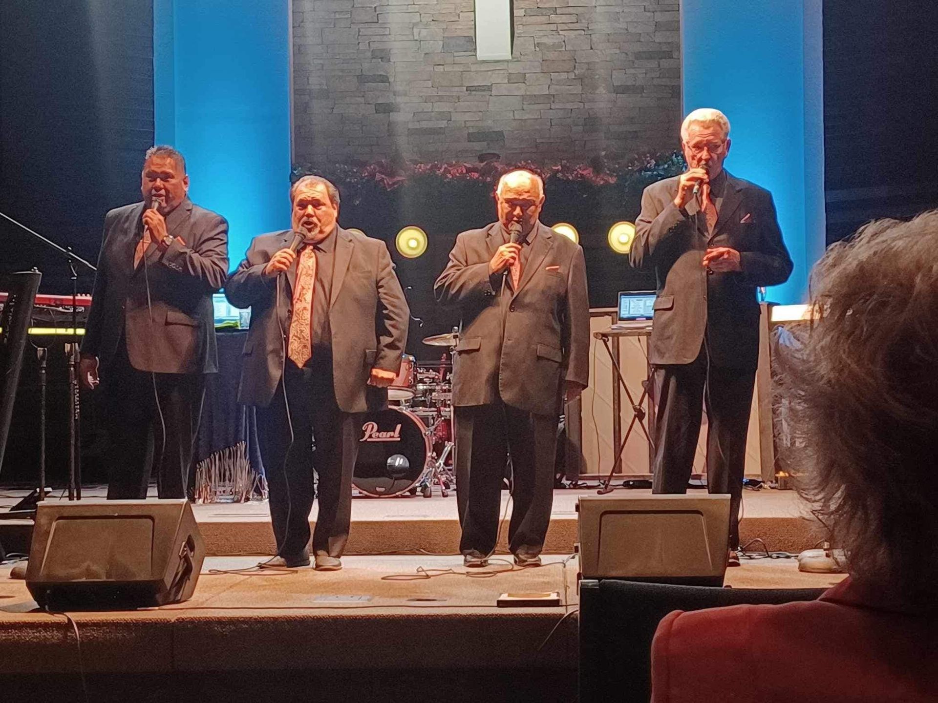 A group of men singing into microphones on a stage