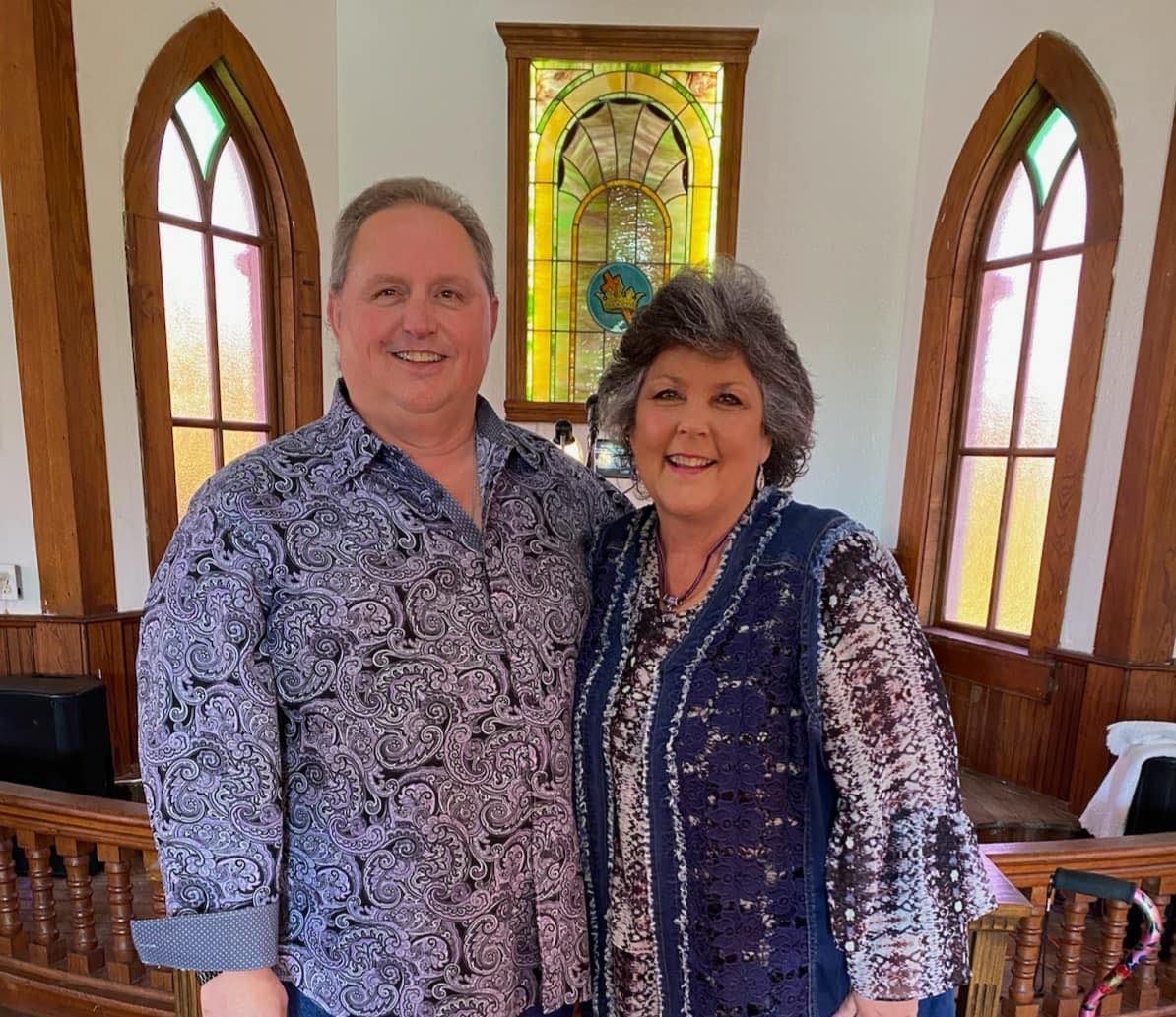 A man and a woman are posing for a picture in front of a stained glass window