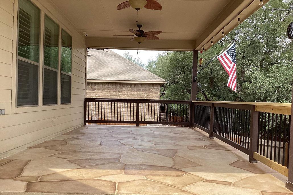 Covered patio with stone floor, dark brown railing, and American flag.