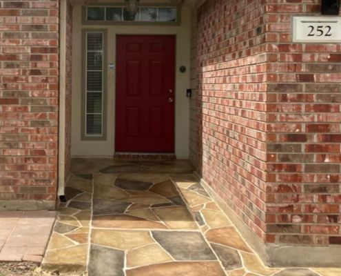 Red front door, brick exterior with stone walkway. House number