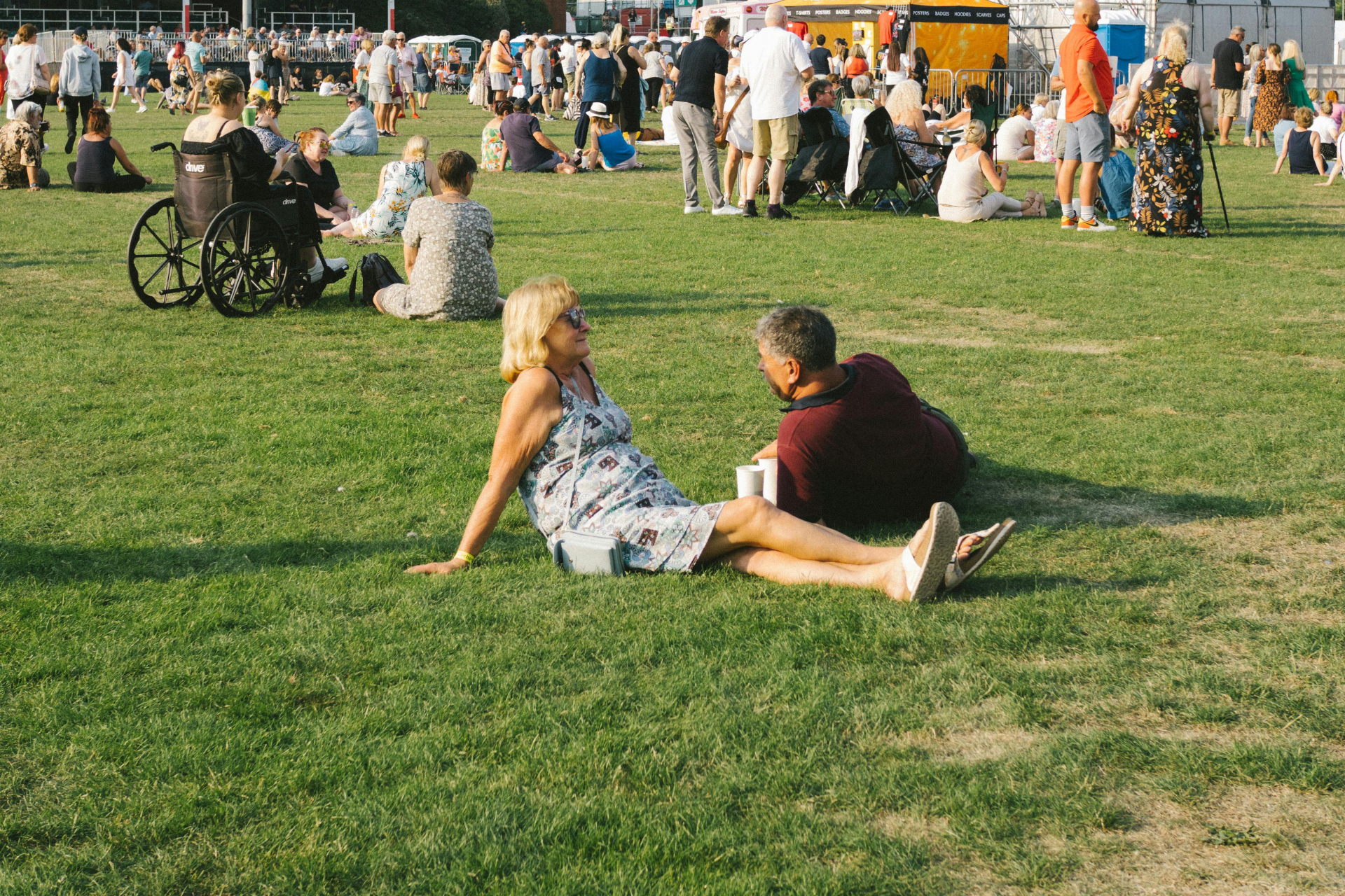 People sitting and relaxing on a grassy field during a public outdoor gathering
