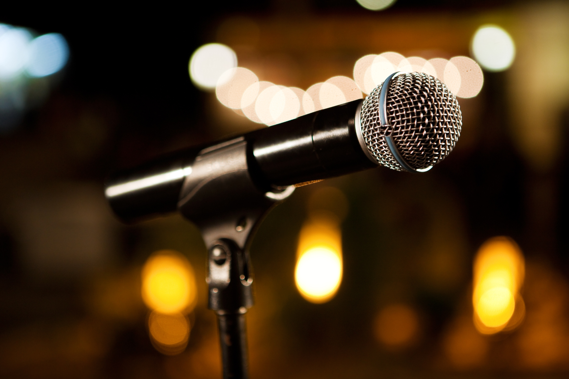Microphone on stand with warm blurred stage lights in the background