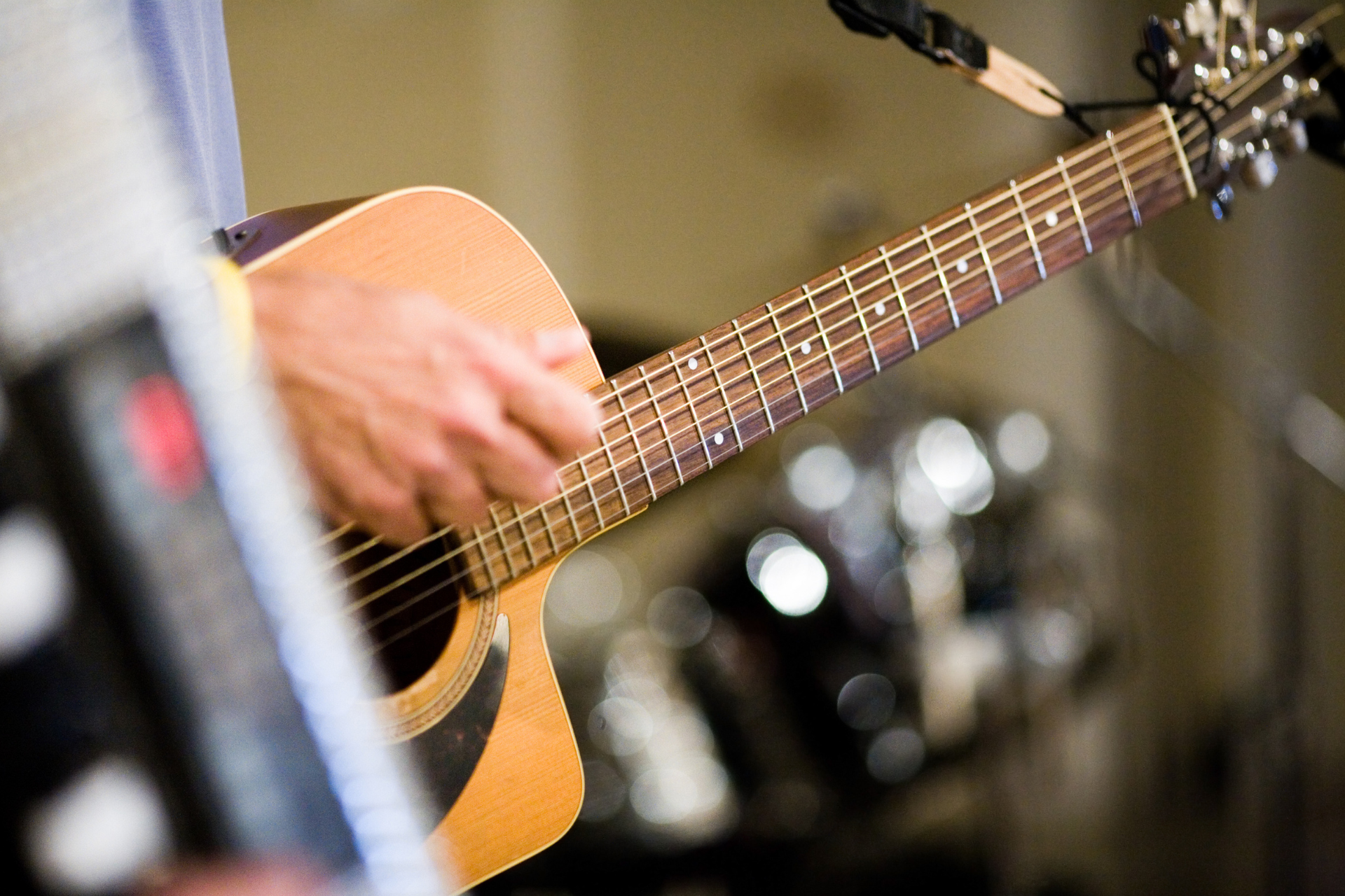 Person playing an acoustic guitar on stage with a microphone nearby