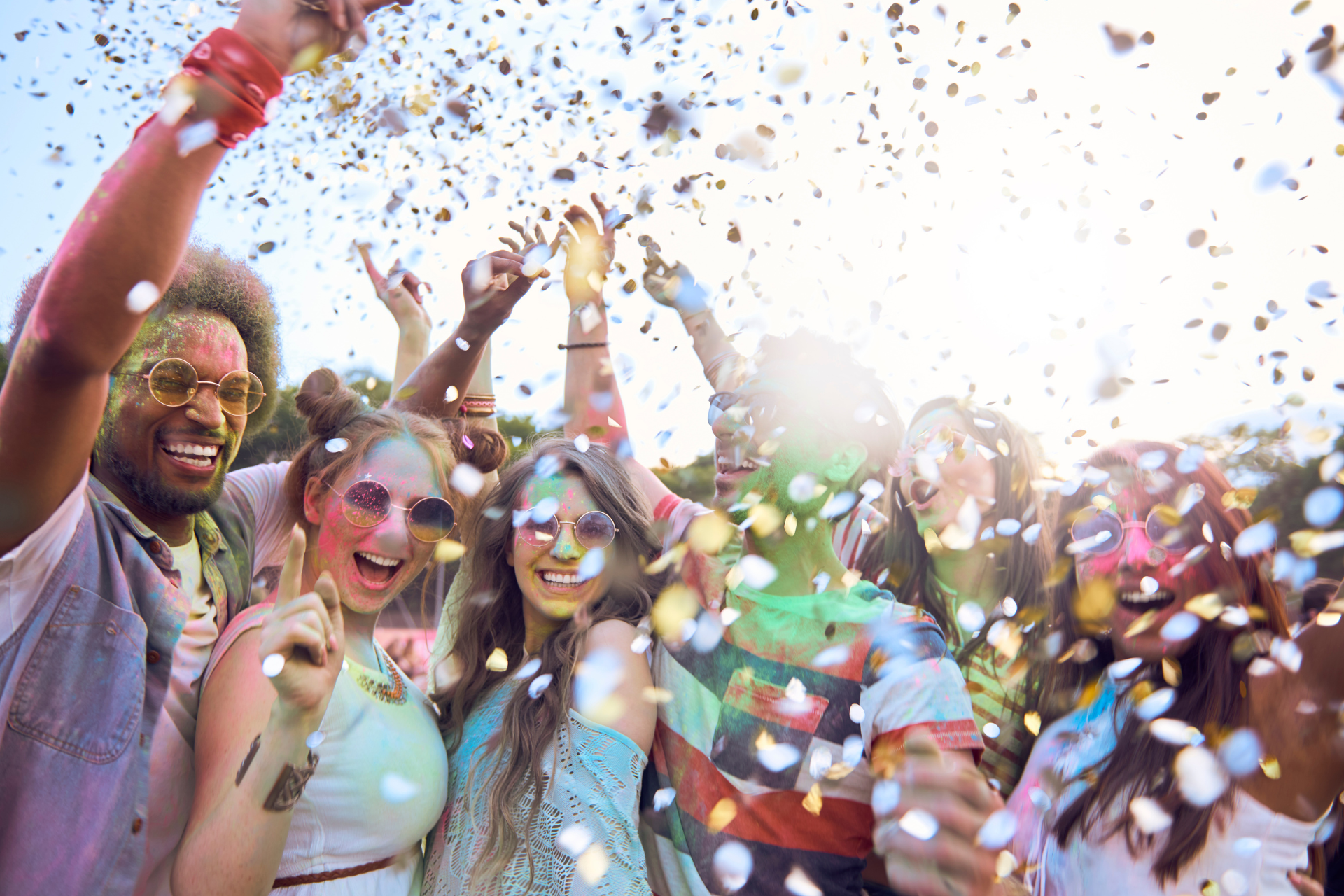 People cheering and throwing confetti at a bright outdoor celebration