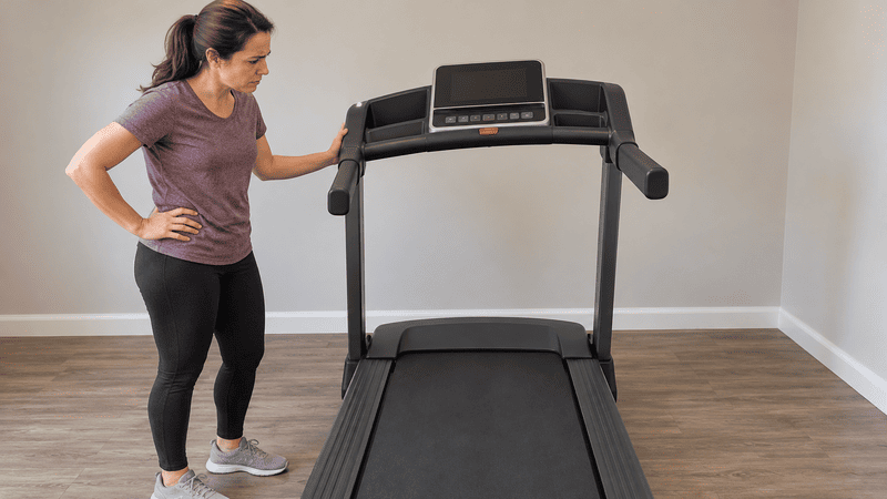 Homeowner inspecting a fully assembled treadmill with a misaligned console frame
