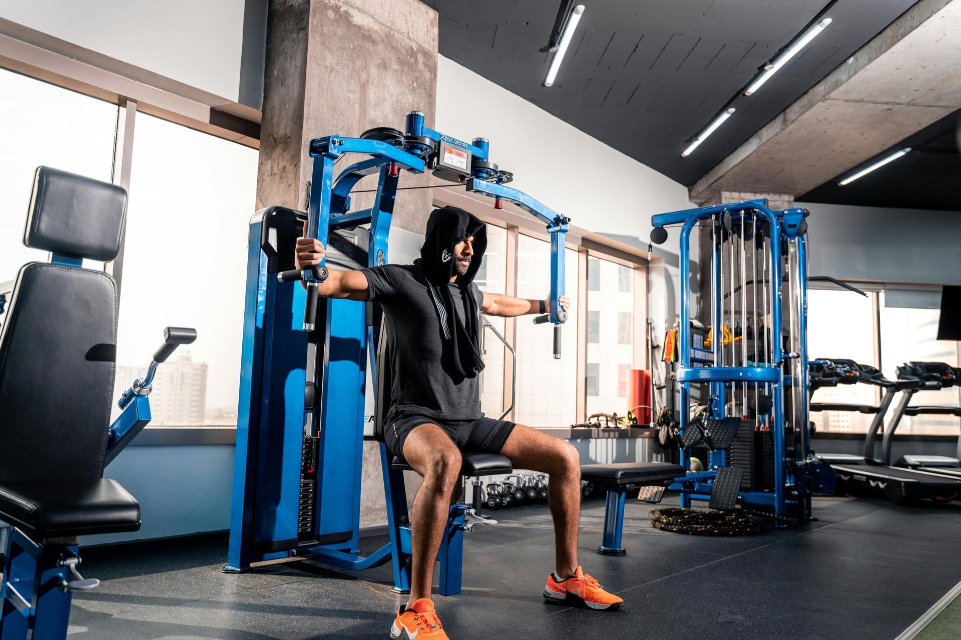 Person using a blue gym machine in a modern fitness room