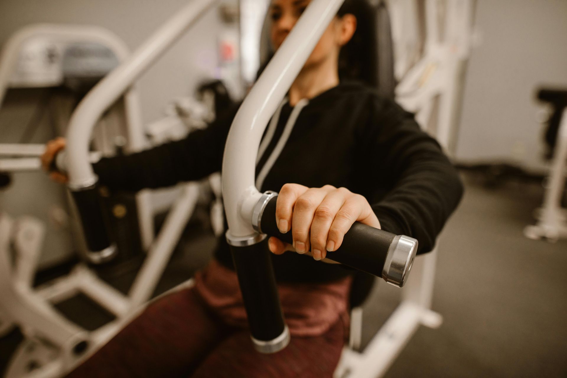 Person gripping gym equipment handles during a workout in a fitness center