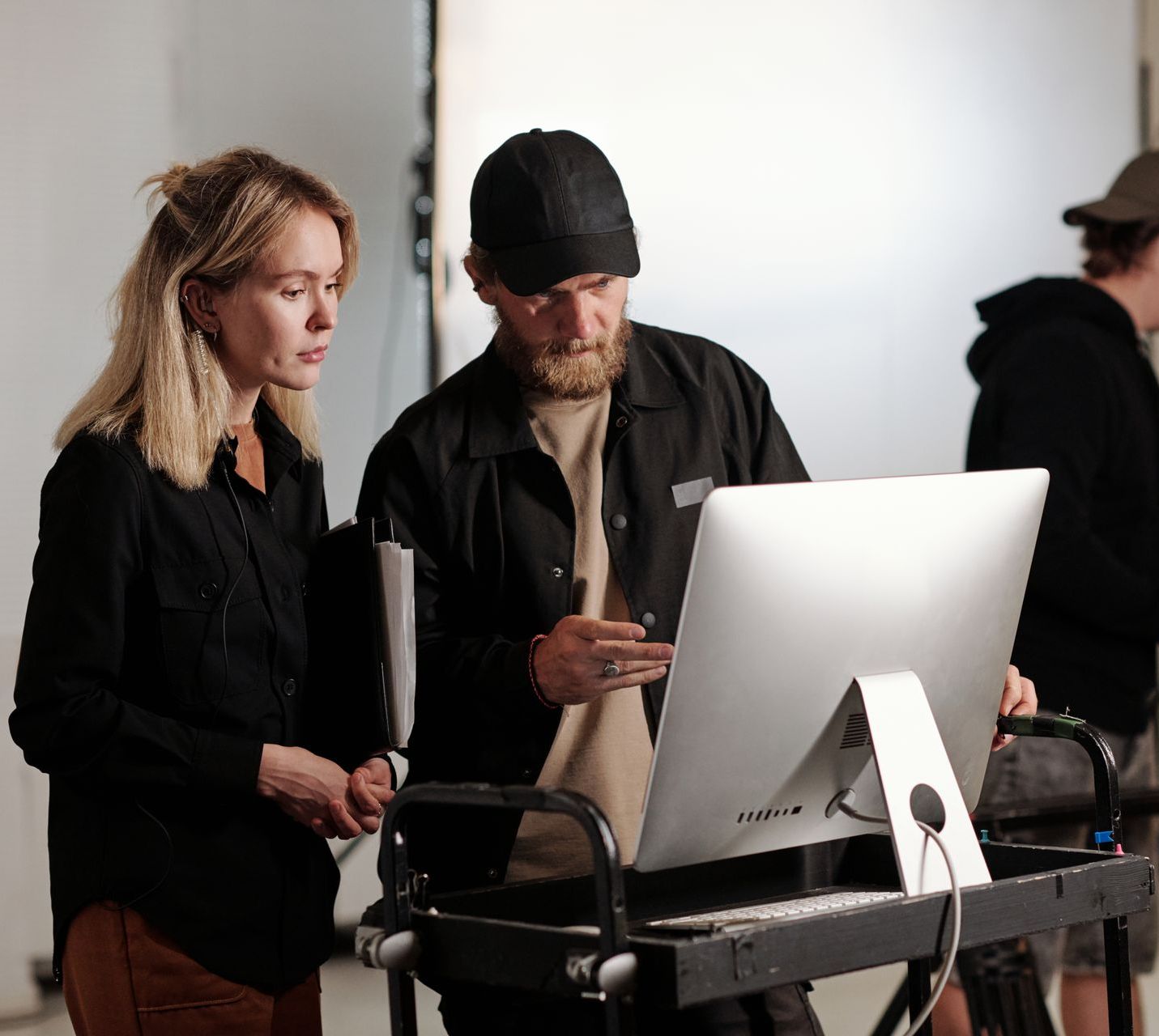 Young videographer and his assistant having discussion in front of computer screen while watching new video branding commercial in studio