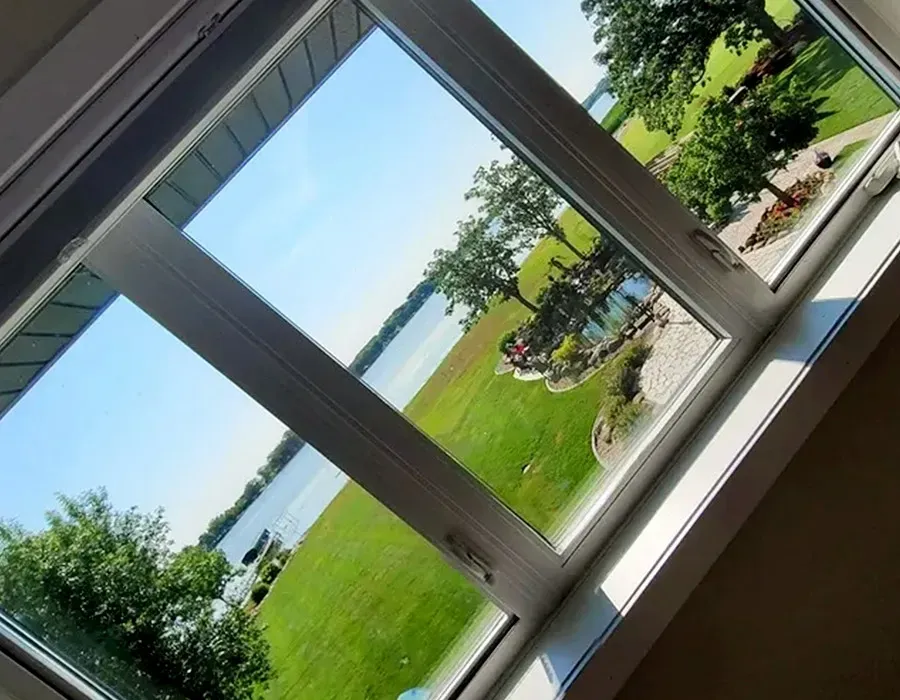 Tilted view through a window of a green lawn and lake on a sunny day.