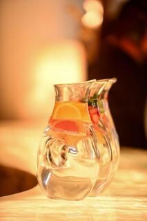 Dos jarras llenas de agua y fruta están sobre una mesa.