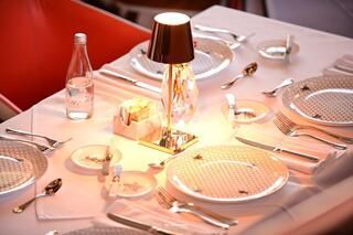 Una mesa con platos, cubiertos y una lámpara sobre ella.