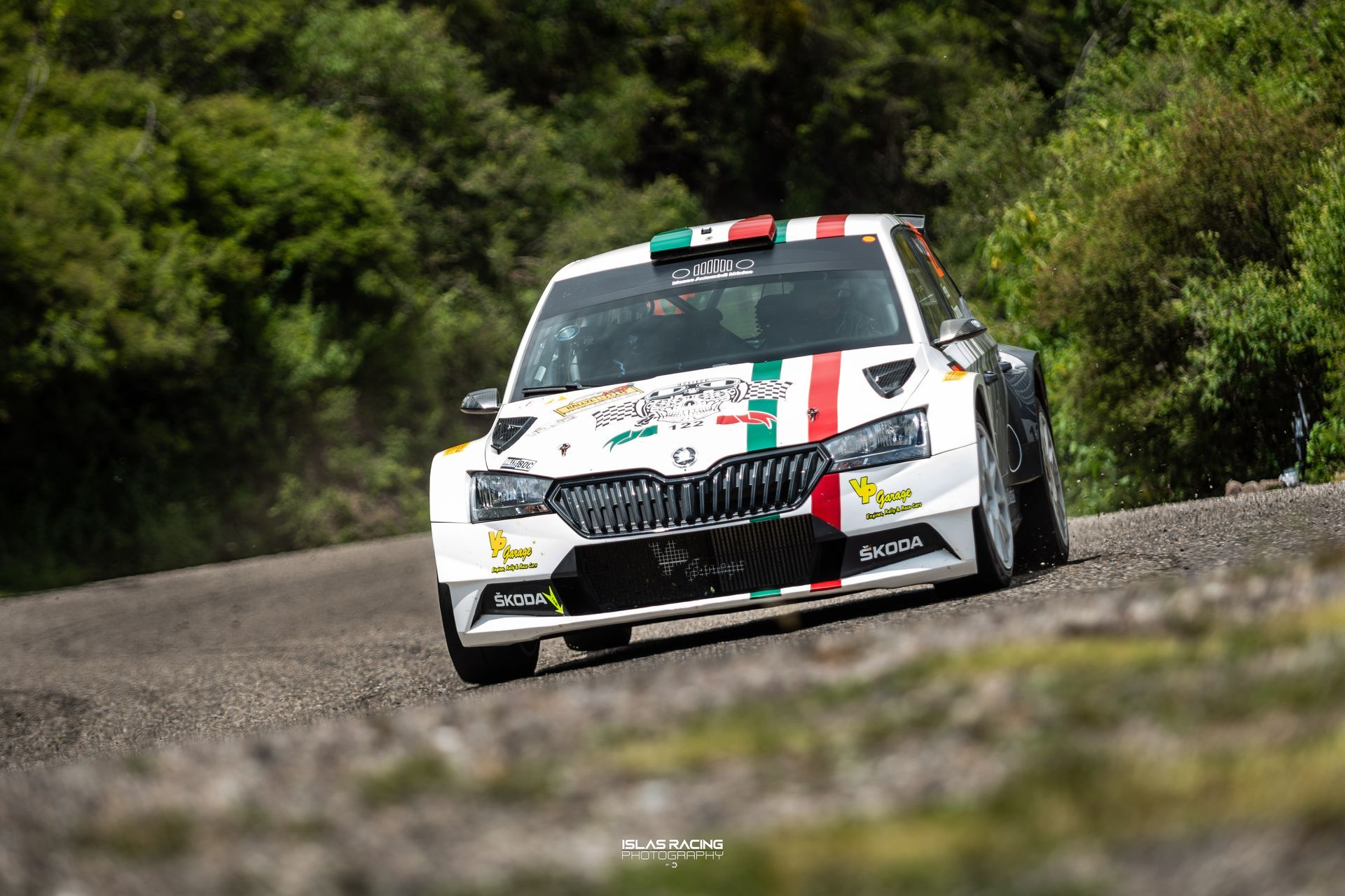 Un coche de carreras blanco circula por un camino de tierra.