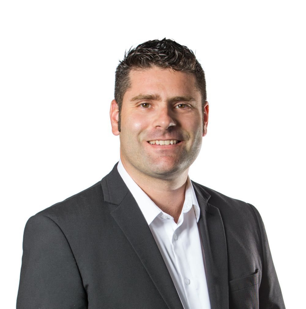 Smiling man in a dark suit and white shirt against a white background