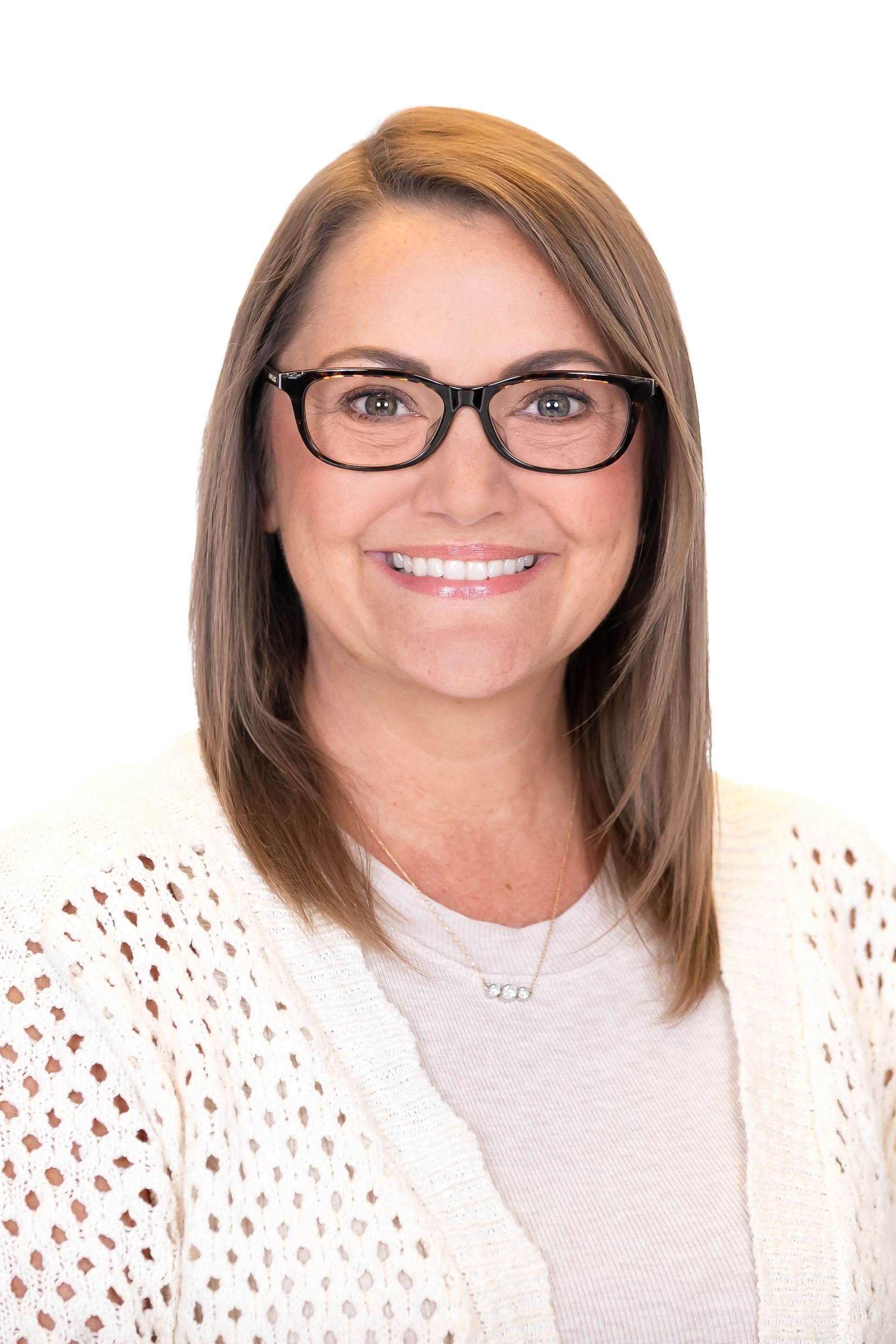 Smiling woman with glasses and shoulder-length hair, wearing a white sweater on a plain white background