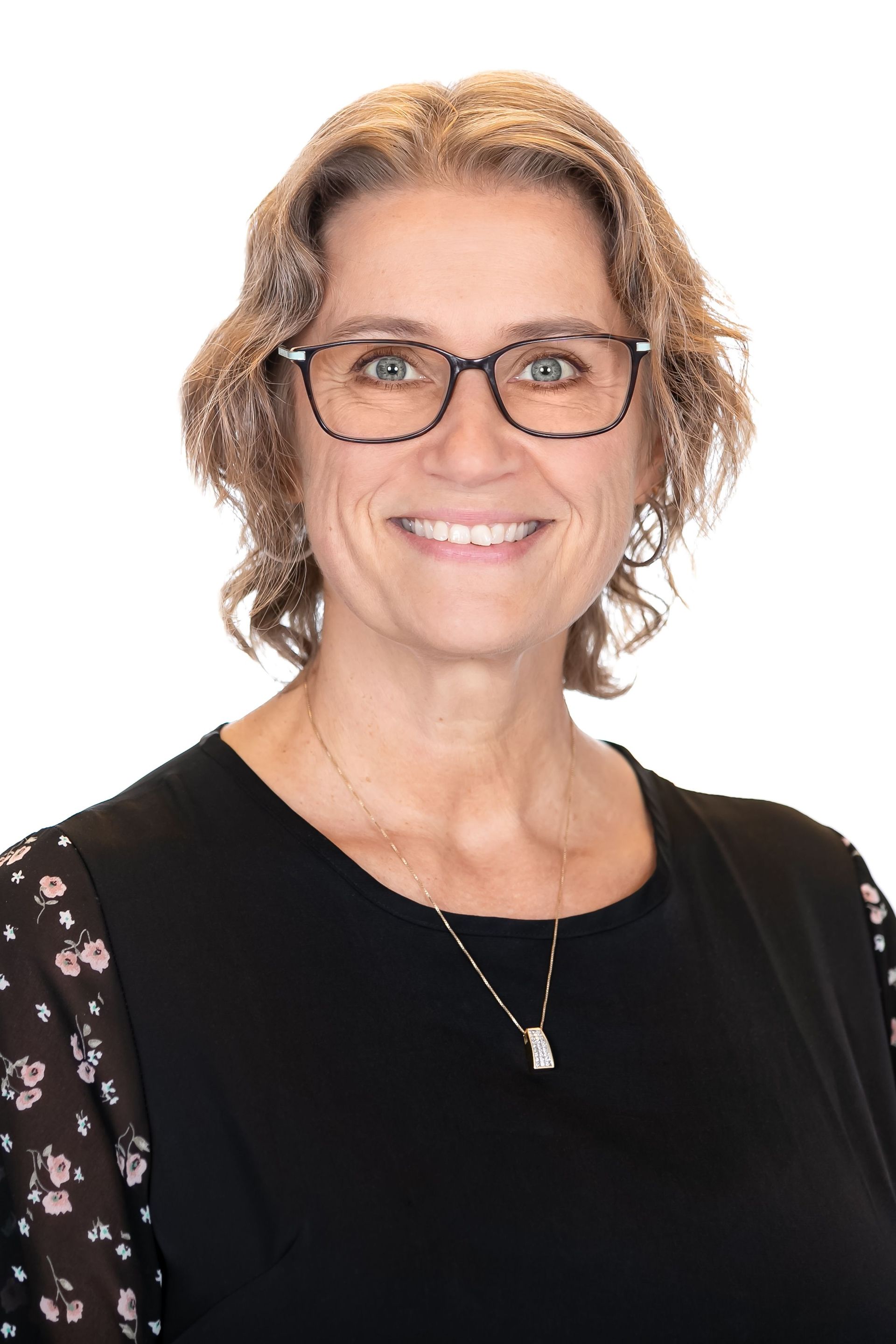 Smiling woman in glasses wearing a black top against a white background