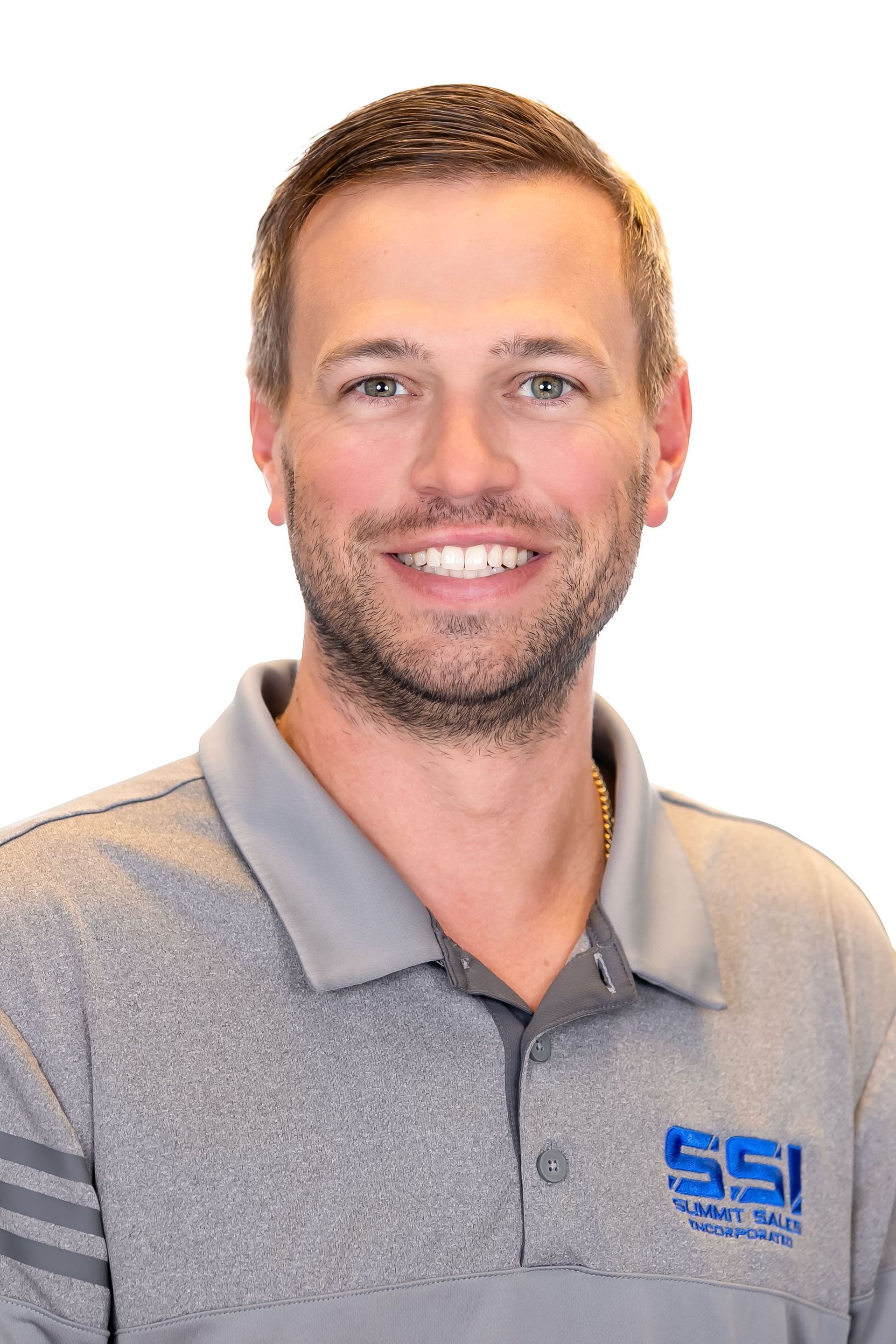 Smiling man in a gray polo shirt with a blue SSI logo against a white background