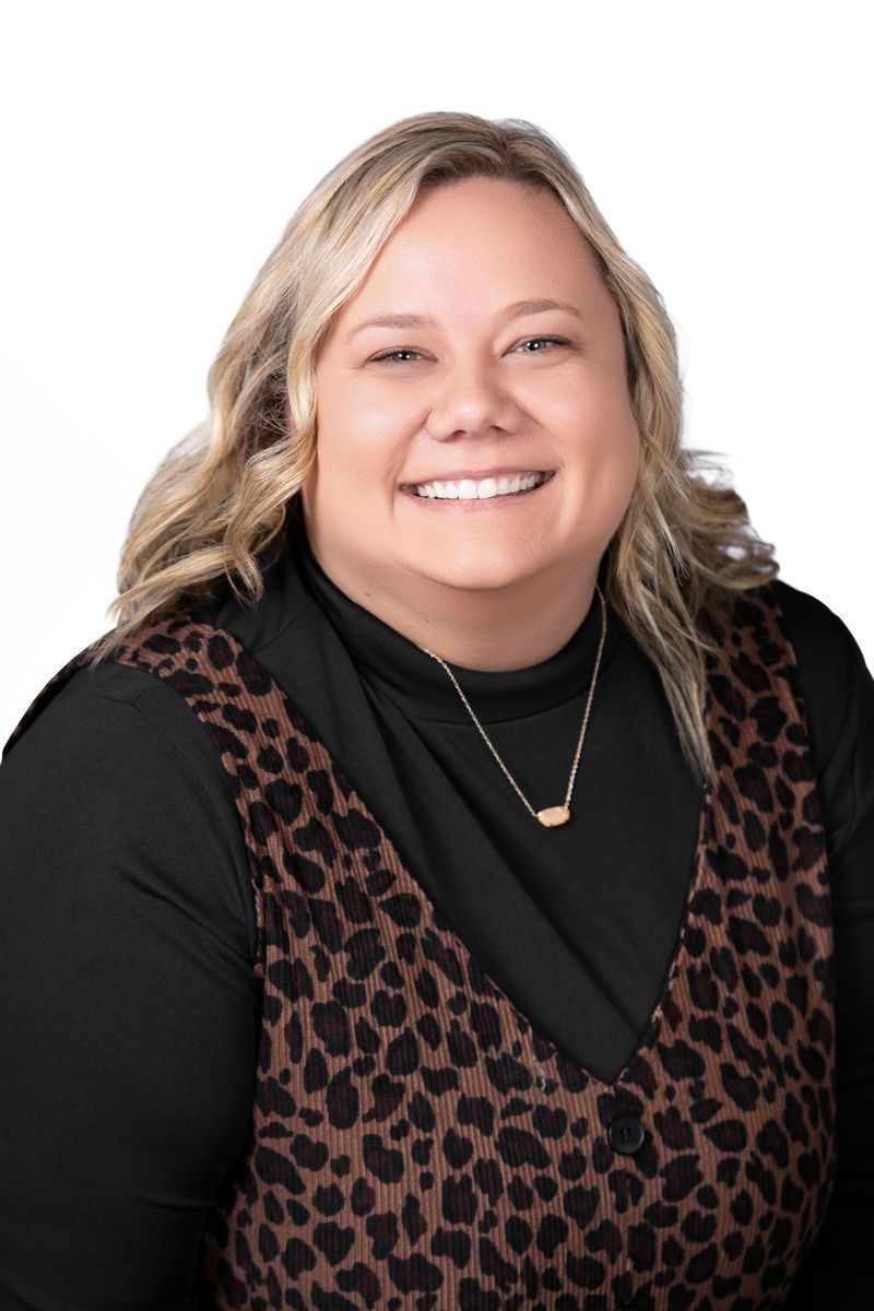 Smiling woman in black top and leopard-print vest against a white background