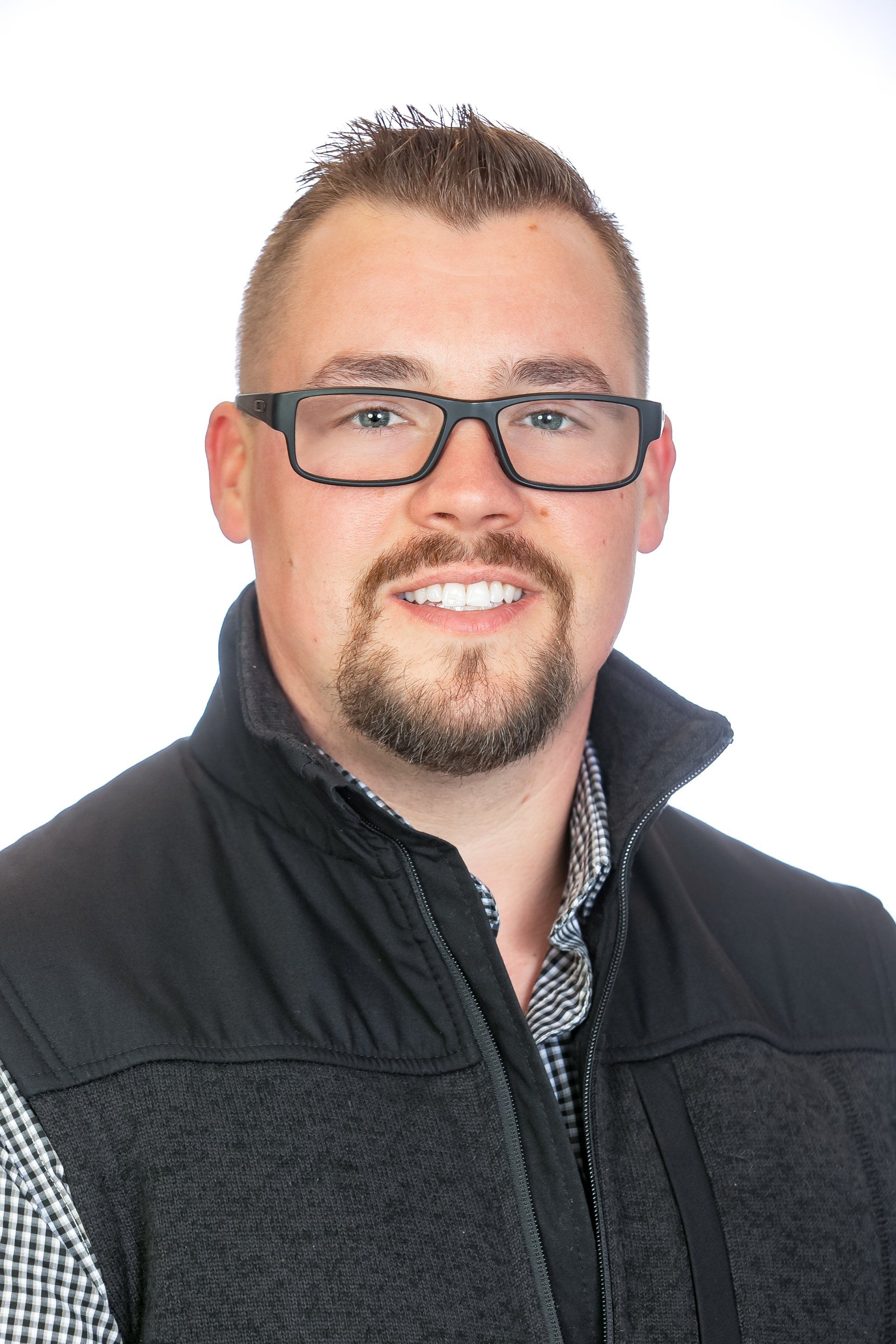 Portrait of a smiling person wearing glasses and a dark jacket on a white background