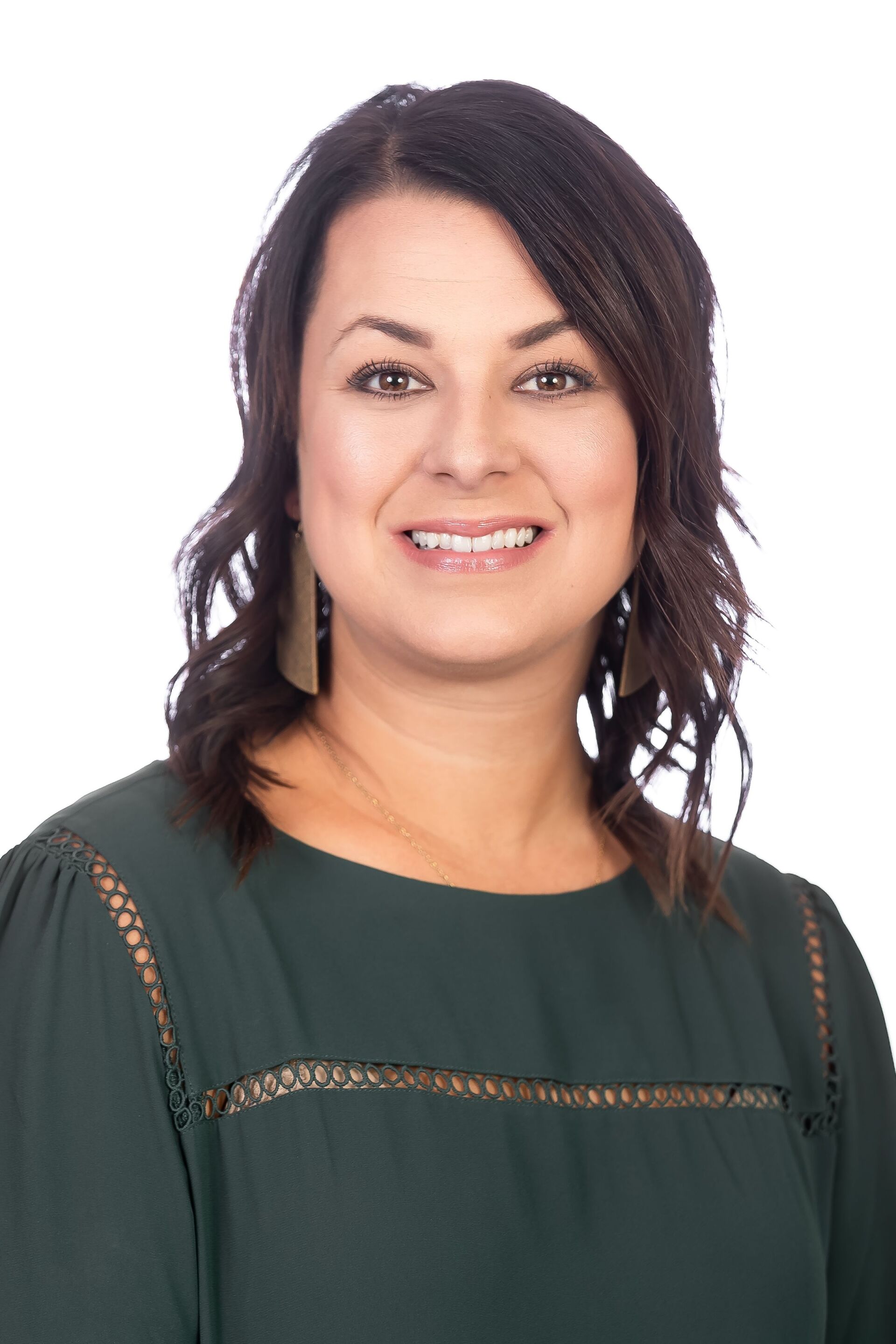 Portrait of a smiling woman with dark wavy hair wearing a dark green top on a white background
