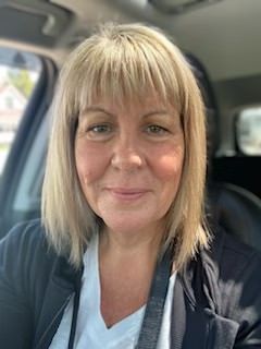 A woman is sitting in the driver 's seat of a car and smiling.
