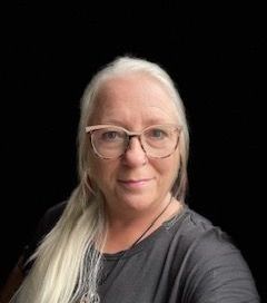 A woman wearing glasses and a black shirt is taking a selfie.