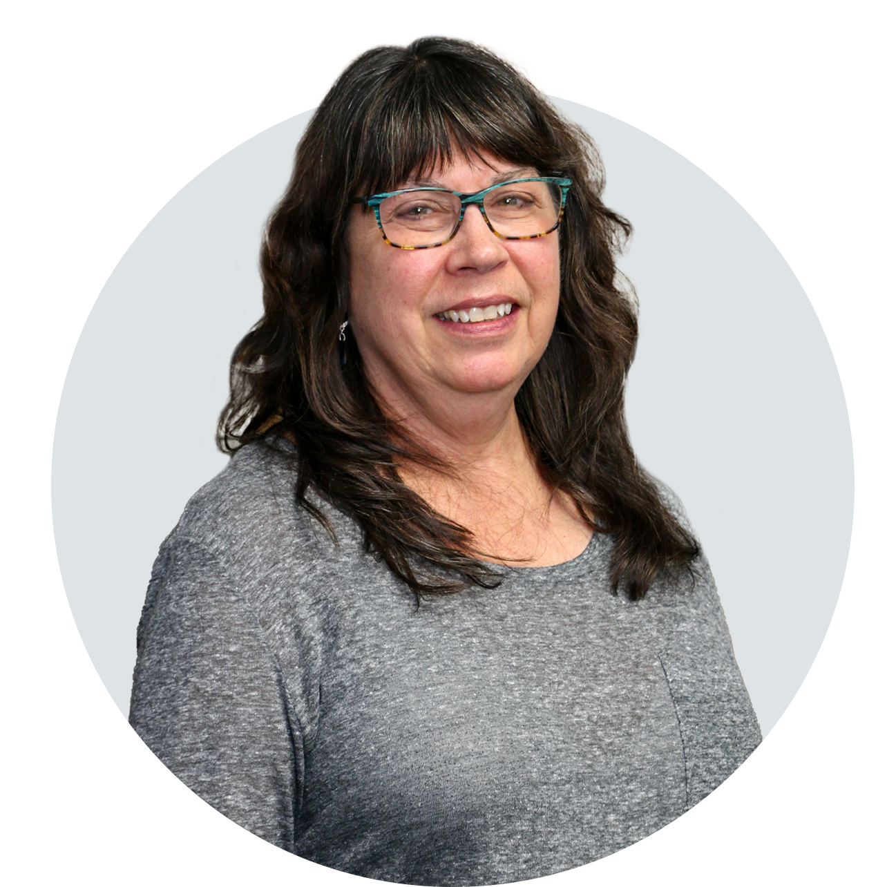 A woman wearing glasses and a grey shirt is smiling in a circle.