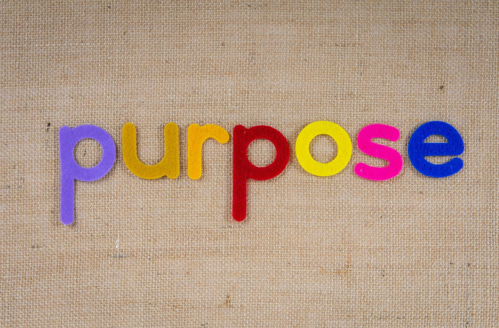 The word purpose is written in colorful letters on a piece of fabric.