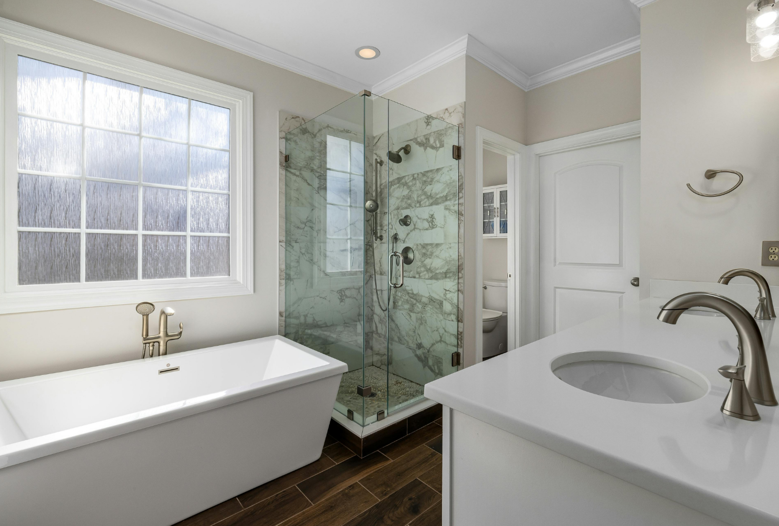 Bright modern bathroom with freestanding tub, glass shower, and white vanity