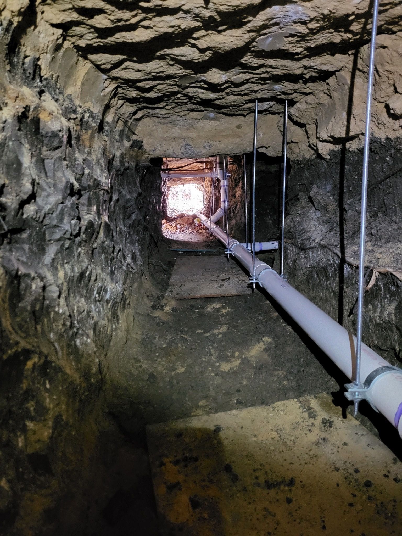 Plumber repairing a leaking sink pipe under a kitchen drain with tools and gloves