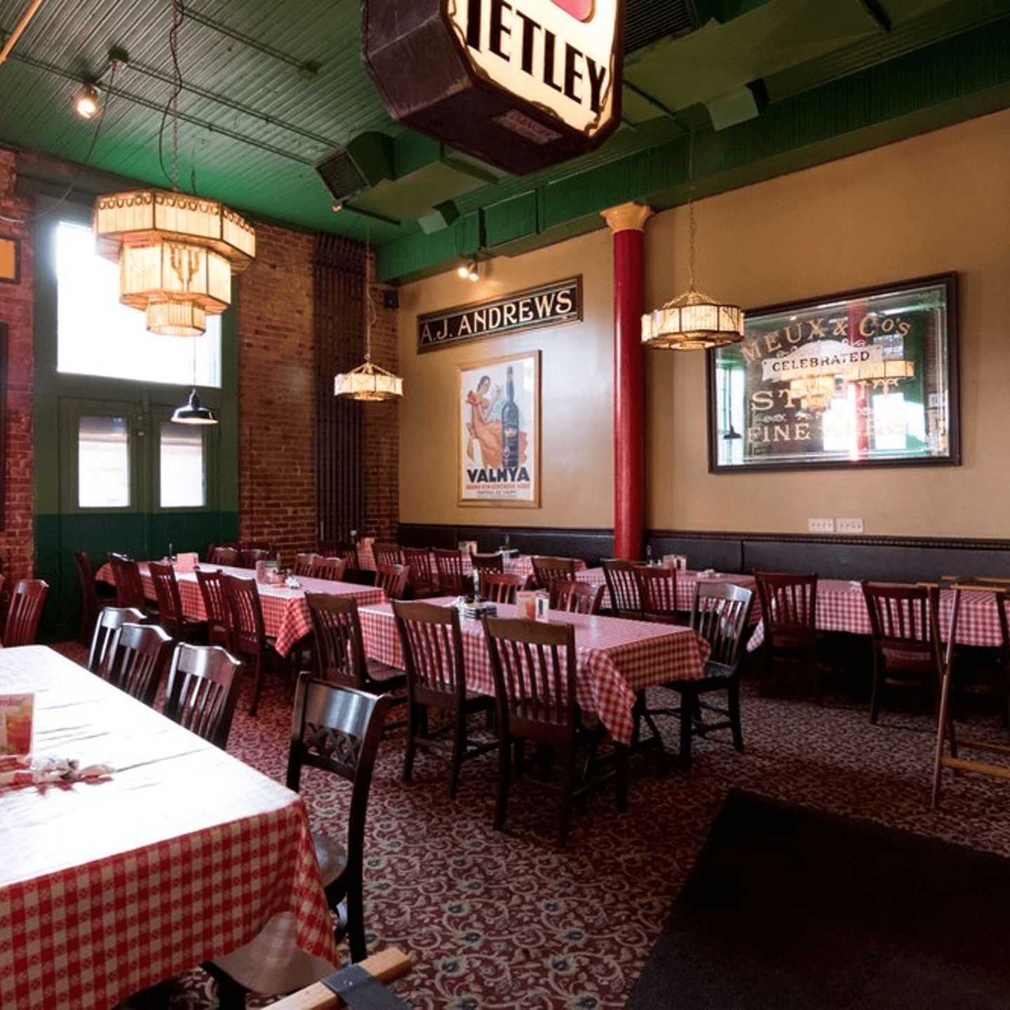 Restaurant dining area with red checkered tablecloths, brick walls, and vintage decor.