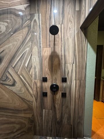 Wood-paneled wall with mounted black circular fixtures and controls beside an open doorway