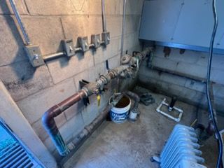 Industrial utility room with pipes, valves, a bucket, and a blue machine on the floor